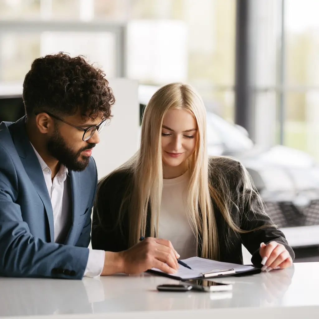 A customer and adviser reviewing paperwork at a desk.