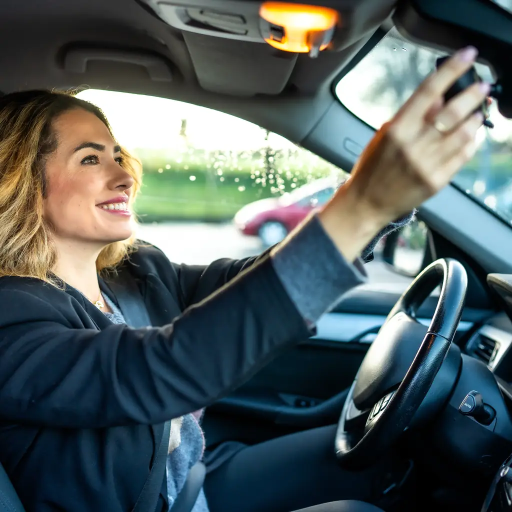 A driver adjusting the interior rearview mirror.