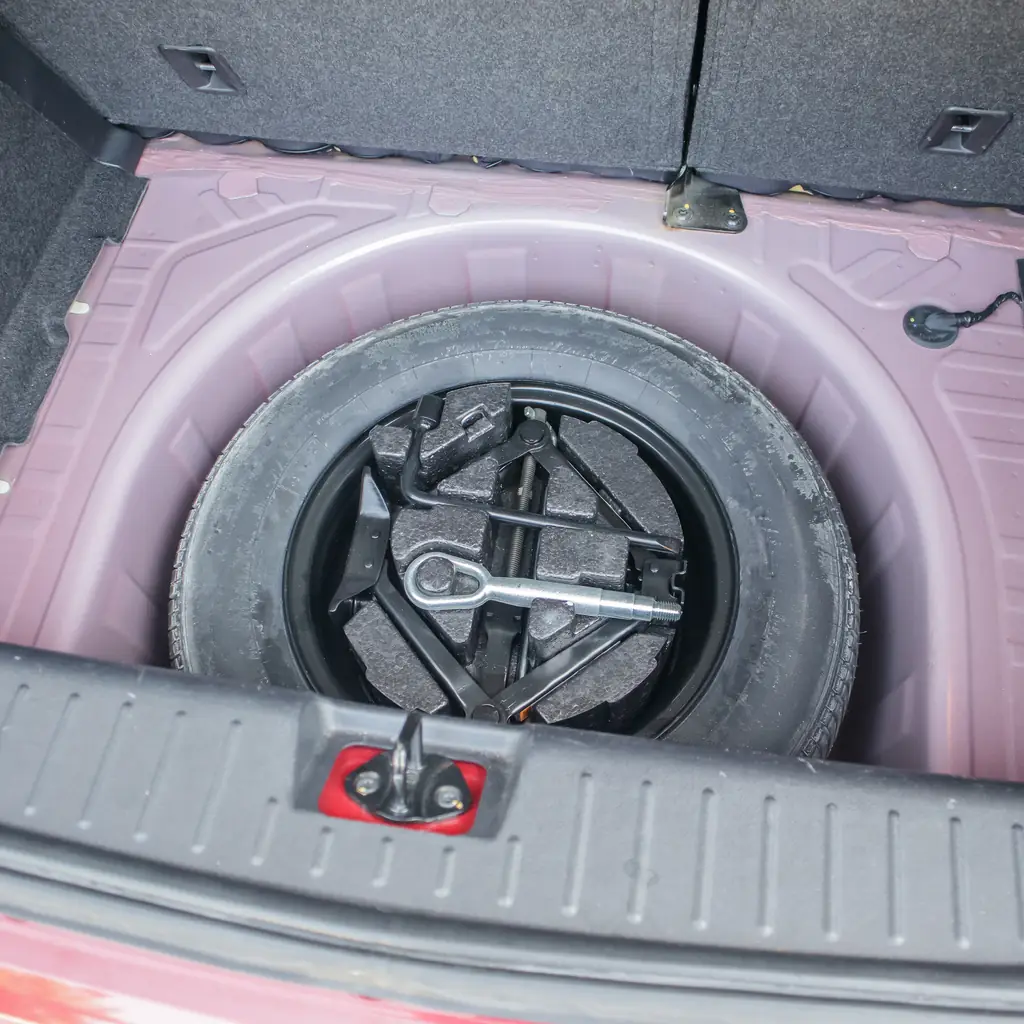A spare tire, jack and tools in a compartment beneath a cargo floor.