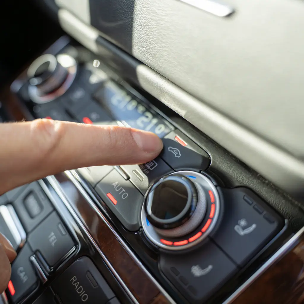 A finger pressing the cabin air-recirculation button.