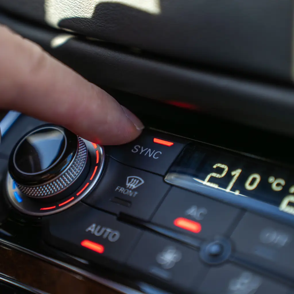 A finger pressing the SYNC button on a dual-zone climate panel.
