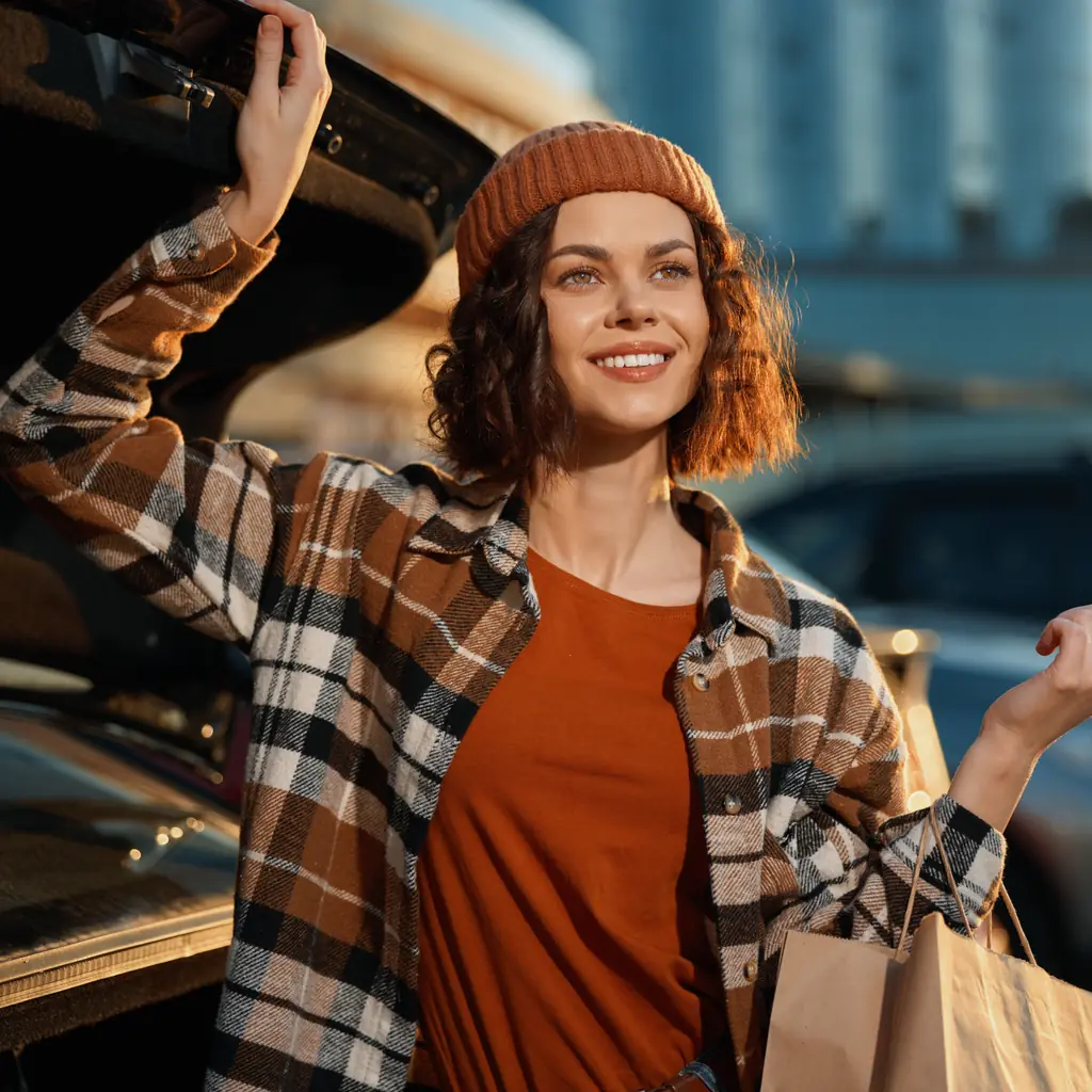 A shopper stands beside an open rear hatch with groceries.