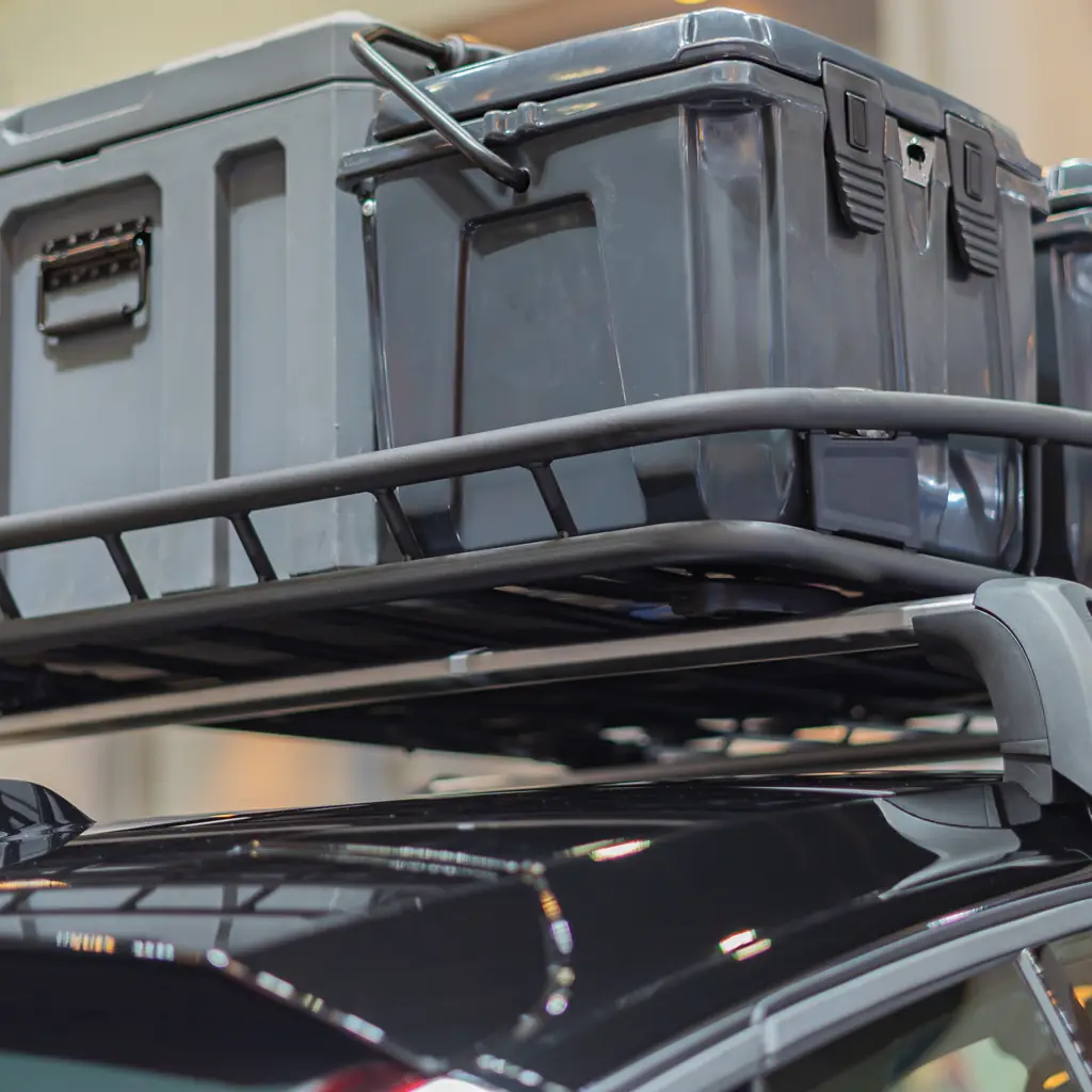 Rigid storage boxes secured on a vehicle roof rack.