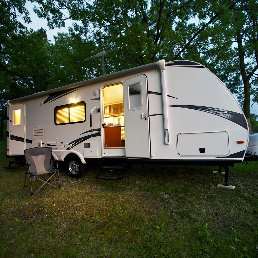 A travel trailer is parked at a campsite with its entry steps lowered.