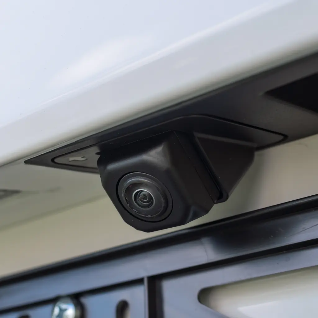 Close-up of a rear-view camera mounted above a license plate.