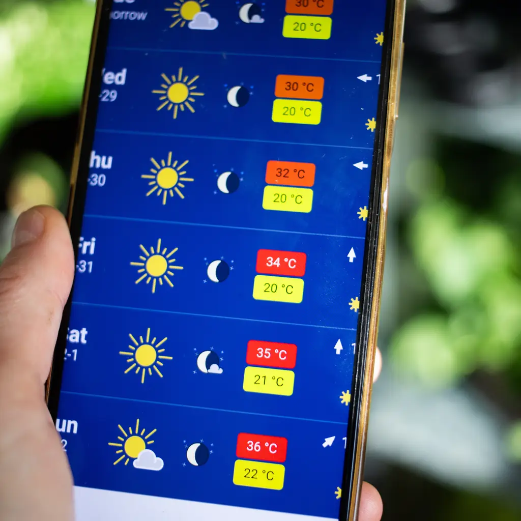 A smartphone showing a weather forecast outdoors.