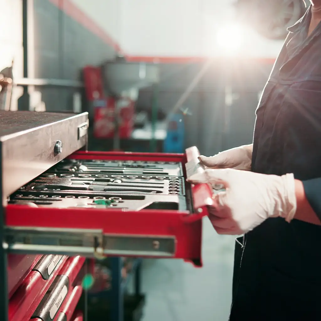 Hands selecting loose tools from a workshop tray.