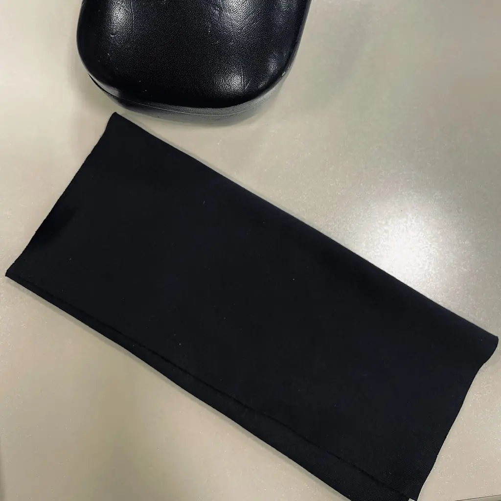 A clean black microfiber cloth beside an eyeglass case.