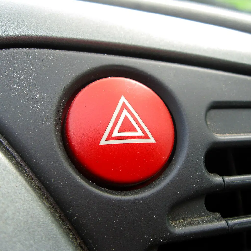 A red hazard-warning button on a car dashboard.