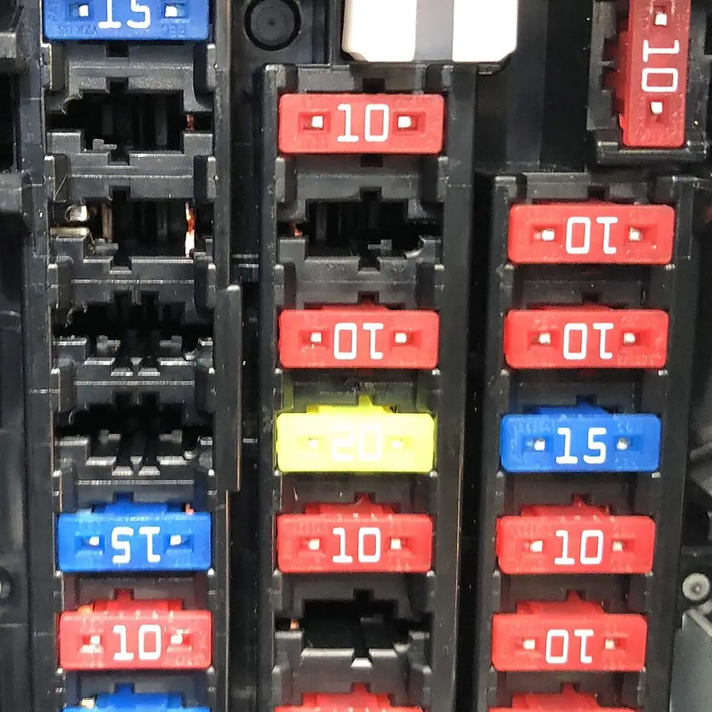 Close-up of a vehicle fuse box with color-coded blade fuses.