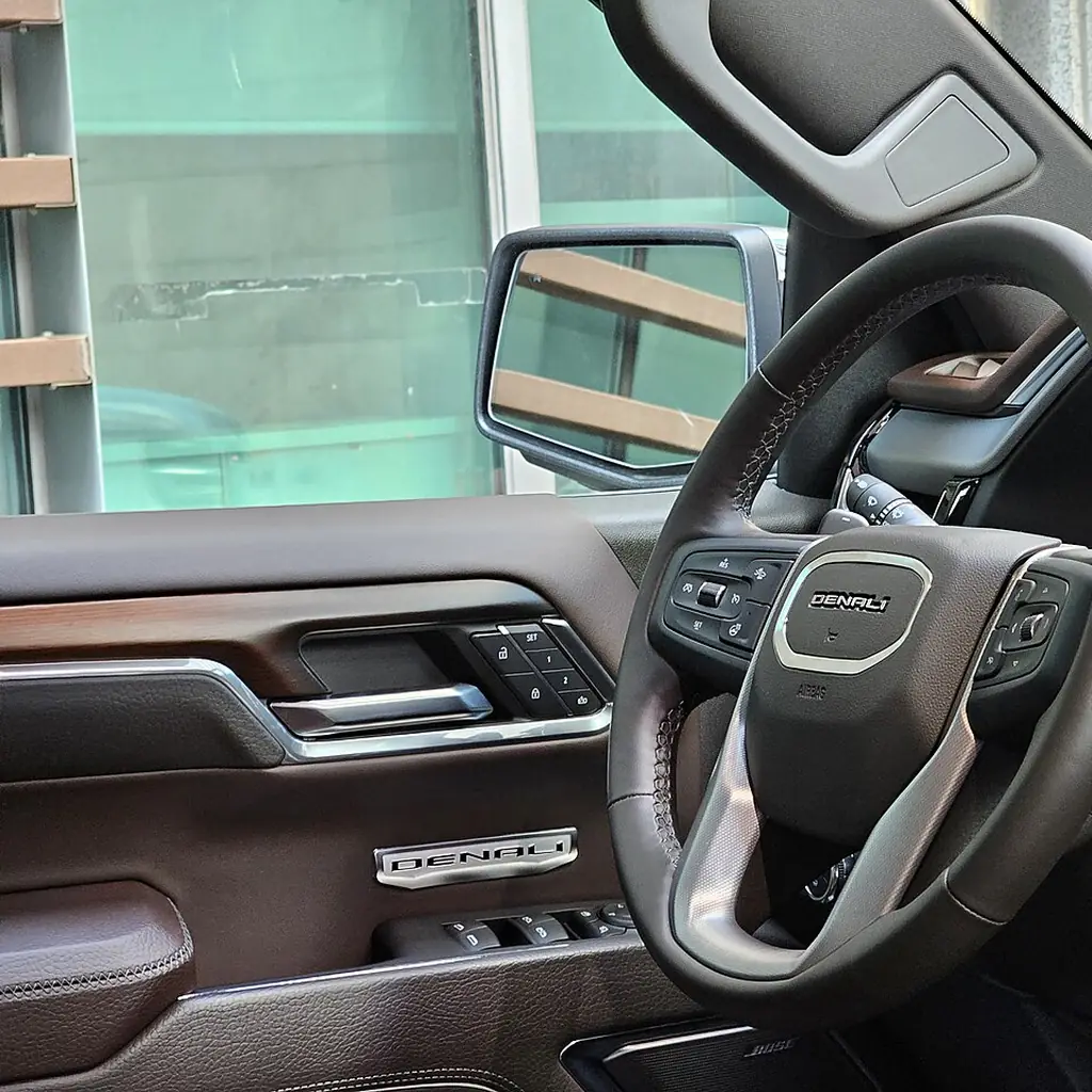 The driver-door controls and exterior mirror of a GMC Sierra Denali.