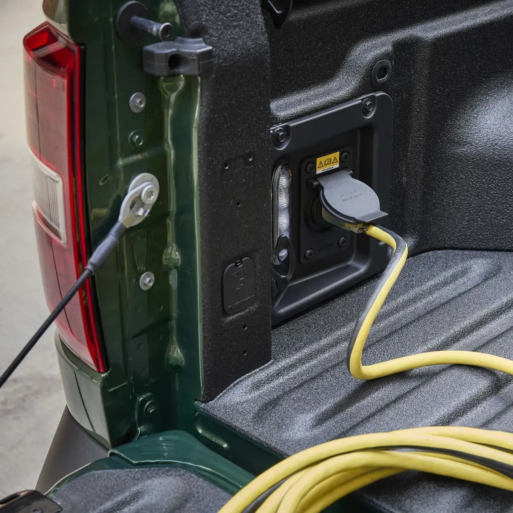 A cable plugged into the available outlet in a Ford Maverick pickup bed.
