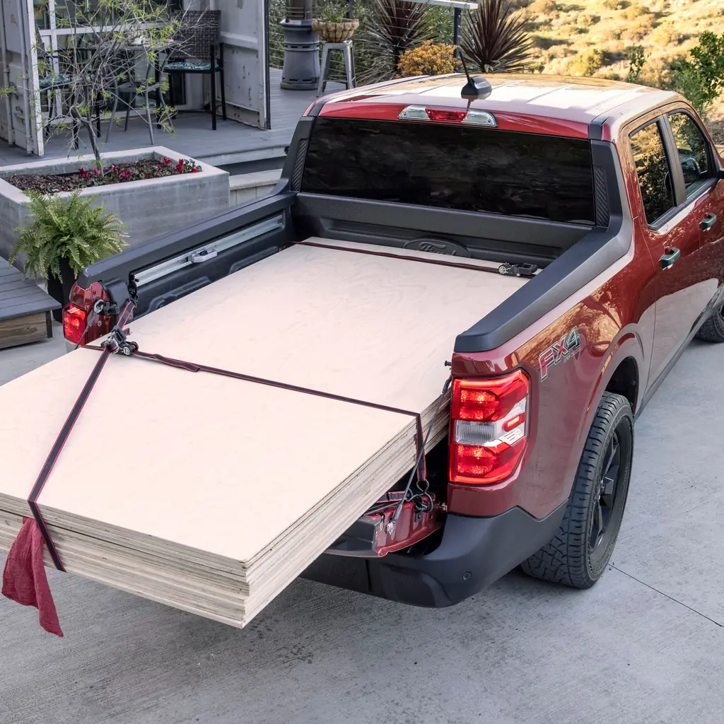Plywood supported across a Ford Maverick bed with its tailgate partly lowered.