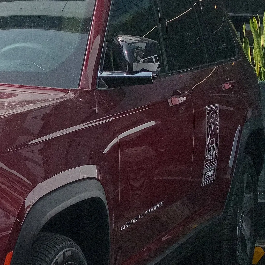 Door and side mirror of a red 2023 Jeep Grand Cherokee Limited.